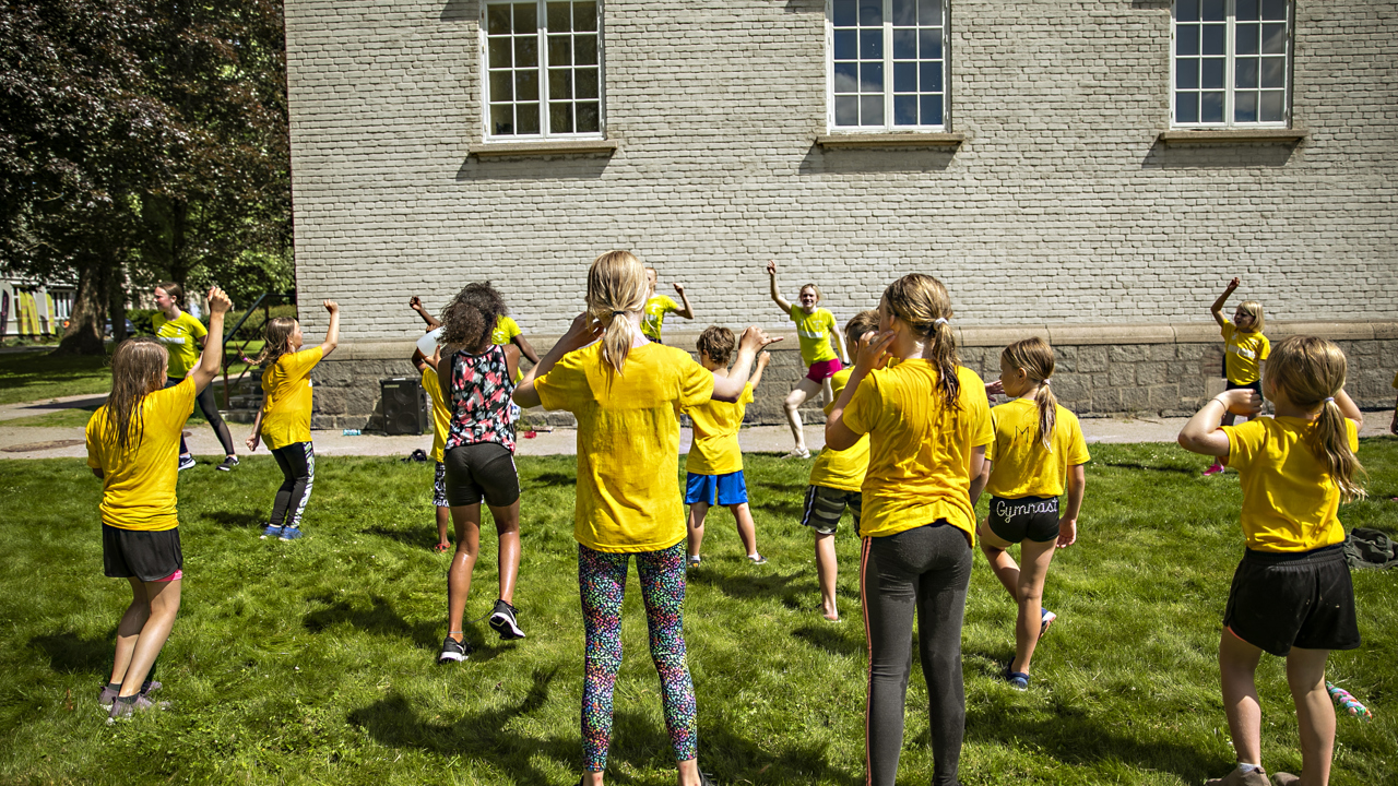 Barn i gule t skjorter danser utendørs
