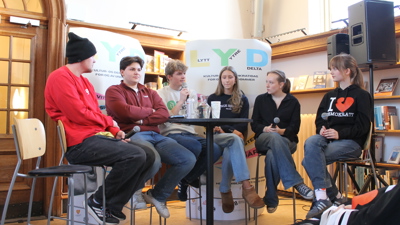 Ungdommer sitter på barstoler i en panelsamtale. 