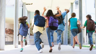 Skolebarn som løper i gangen sett bakfra