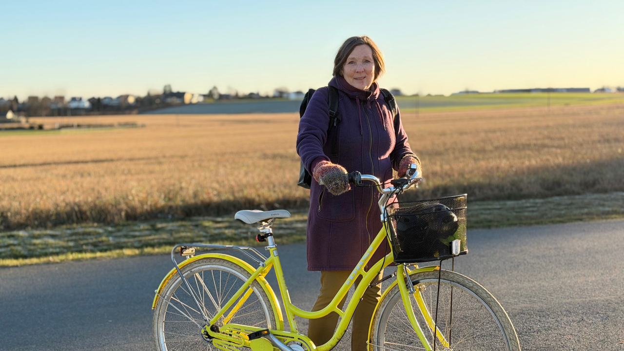 Dame poserer i høstsolen med en gul sykkel 