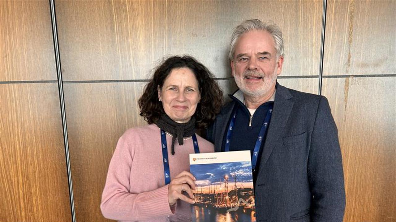 Bilde av to personer, en kvinne og en mann som holder opp et magasin. 