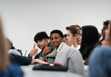 Elever følger med på undervisning og titter i kamera og smiler 