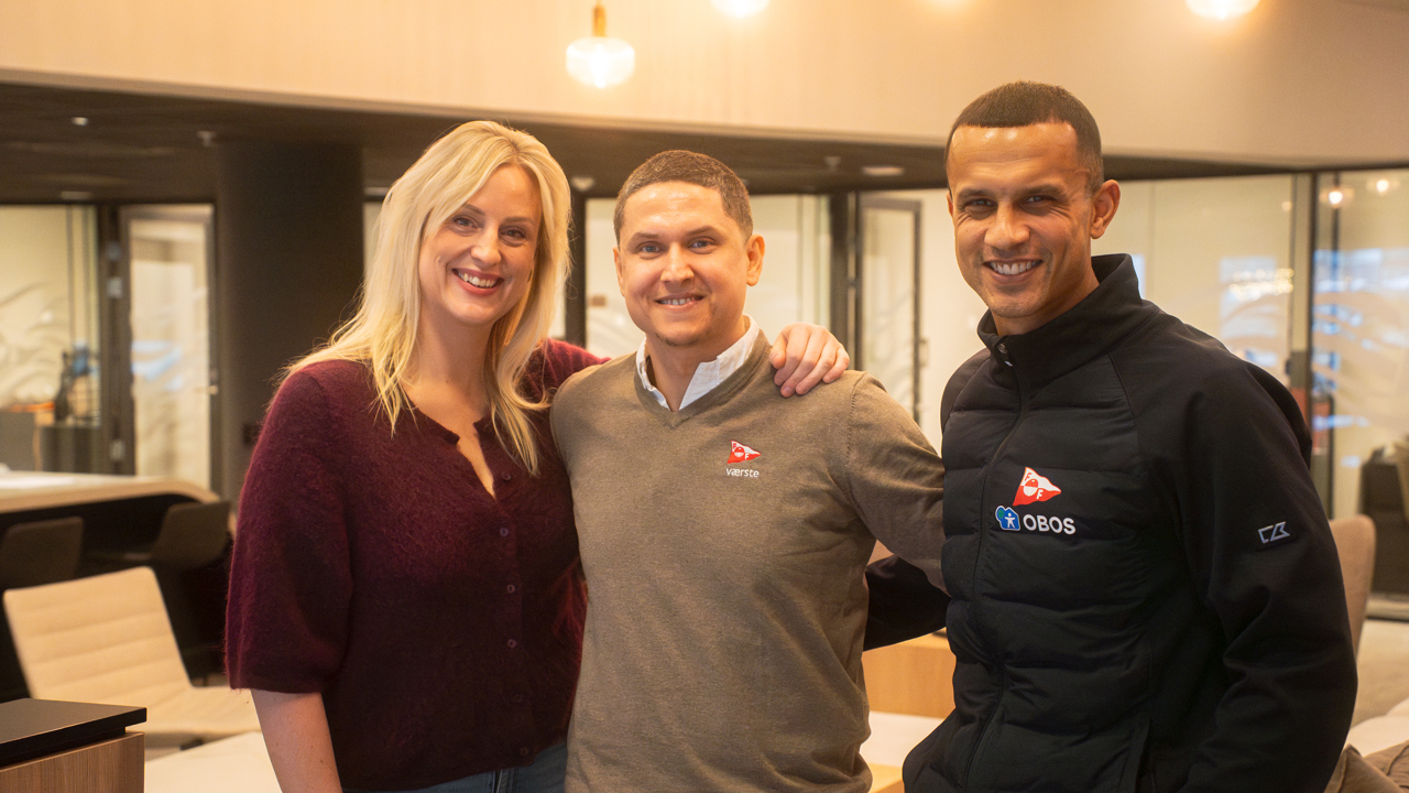 Tre blide personer smiler mot kamera. 